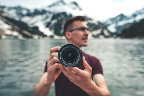 Stock image of a photographer with only the lens of his camera in focus