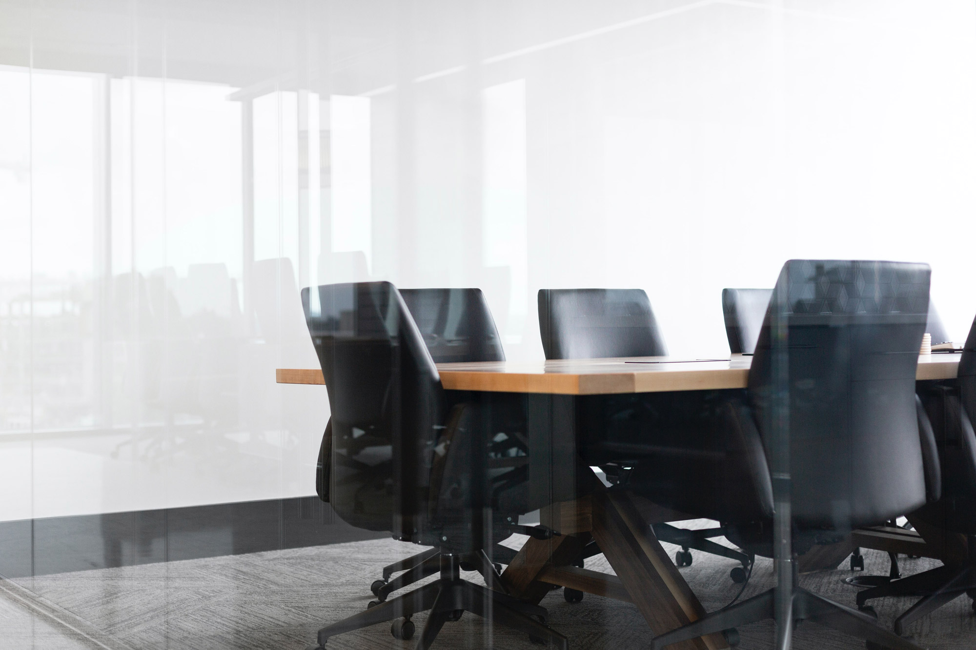 Stock image of some chairs around a conference room table through glass.